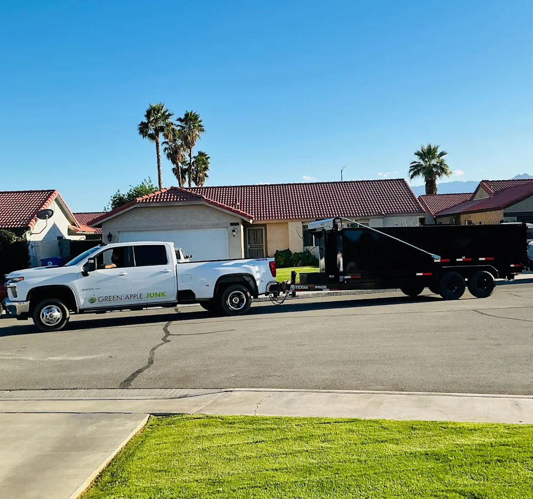 White Green Apple pickup truck with dump trailer in front of home with palm trees
