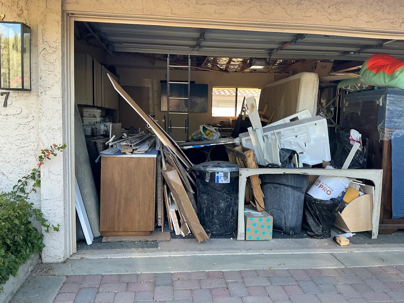 Garage cleanout job — full of furniture, boxes, and household junk before removal