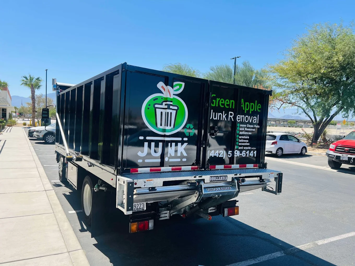 Green Apple branded dumpster trailer rear view showing logo and phone number (442) 599-6141